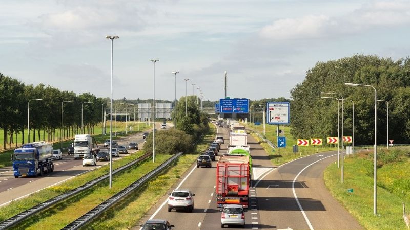 Photo of the A58. You can see cars and trucks driving over the asphalt.