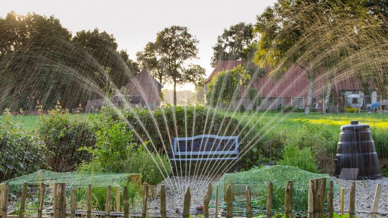 Foto van een tuin waar een sproeier de tuin besproeid.