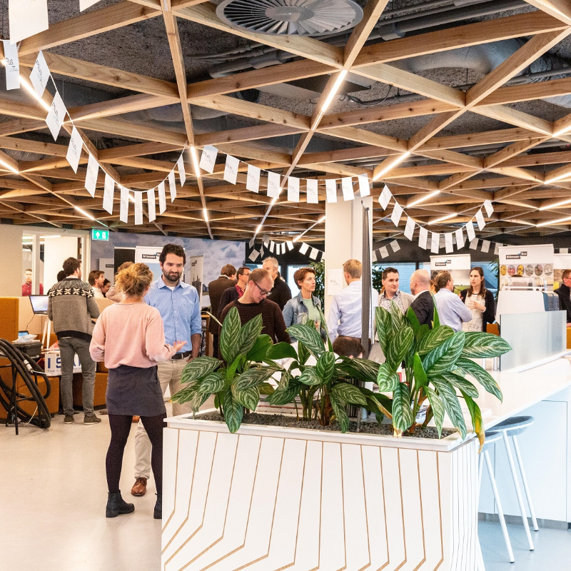Picture of our lobby of the head office in Deventer, the Netherlands. Colleagues are having a gathering and are chatting with each other in small groups, while standing up.