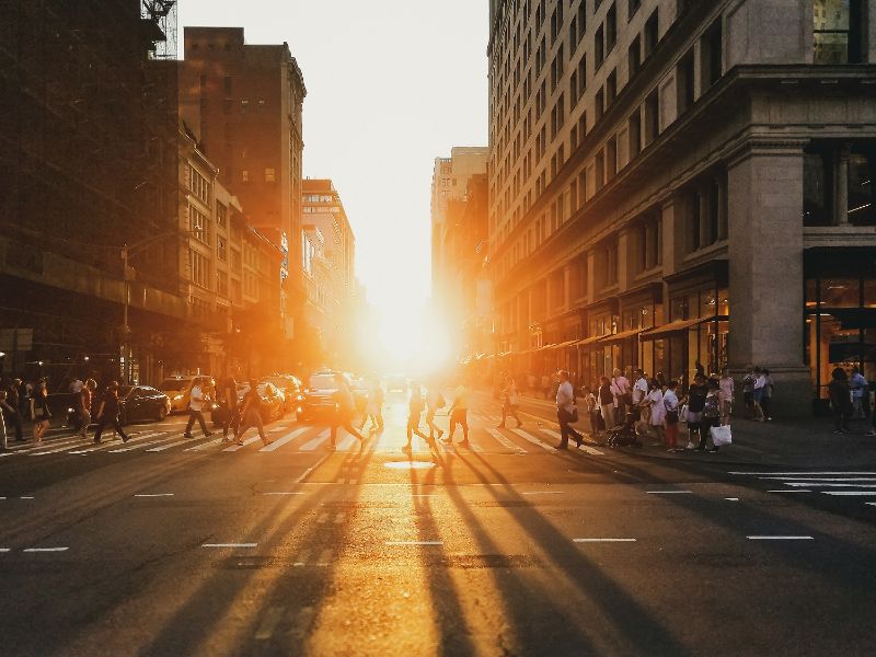 A photo of a city. You can see the sun between the buildings.