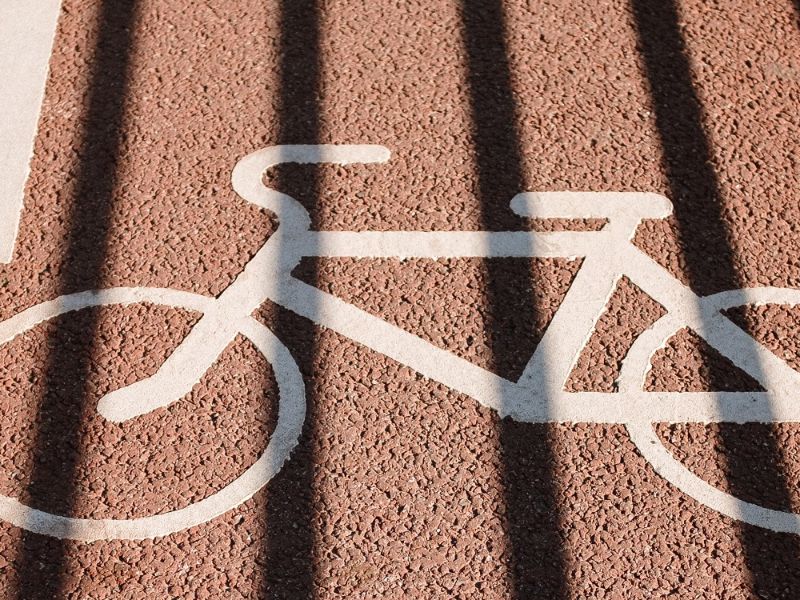Een witte getekende fiets op rood asfalt.
