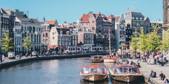 A photo of the canals of Amsterdam. The sun is shining.