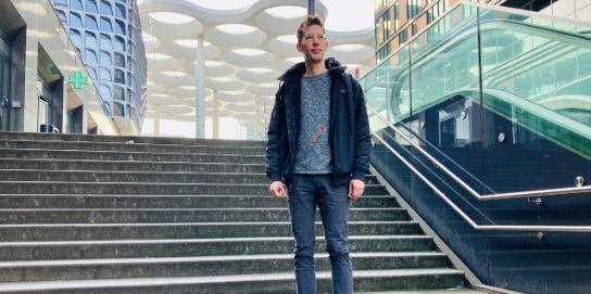 A photo of Laurens Versluis. He is standing in front of a staircase.