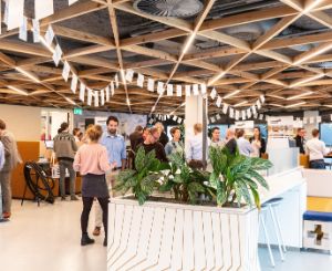 Picture of our lobby of the head office in Deventer, the Netherlands. Colleagues are having a gathering and are chatting with each other in small groups, while standing up.