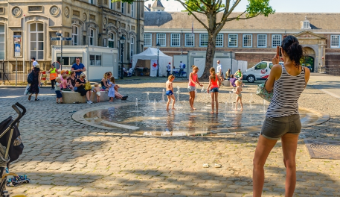 Children playing under a fountain in summer.