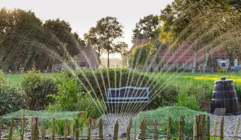 Photo of a garden where a sprinkler is watering the garden.