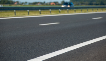 A photo of the asphalt with white lines of a highway.