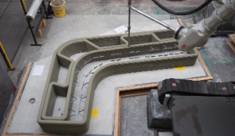 A photo of a 3D concrete printer. The printer is working.