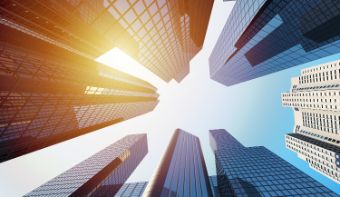 A photo taken from the ground up in the air. You can see the sun and buildings. 