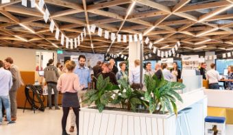 Picture of our lobby of the head office in Deventer, the Netherlands. Colleagues are having a gathering and are chatting with each other in small groups, while standing up.
